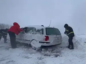 Poliţişti dezzăpezind o maşină blocată în nămeţi, în Botoşani - Foto: captură video Monitorul de Botoşani