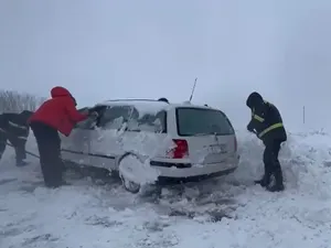 Poliţişti dezzăpezind o maşină blocată în nămeţi, în Botoşani - Foto: captură video Monitorul de Botoşani