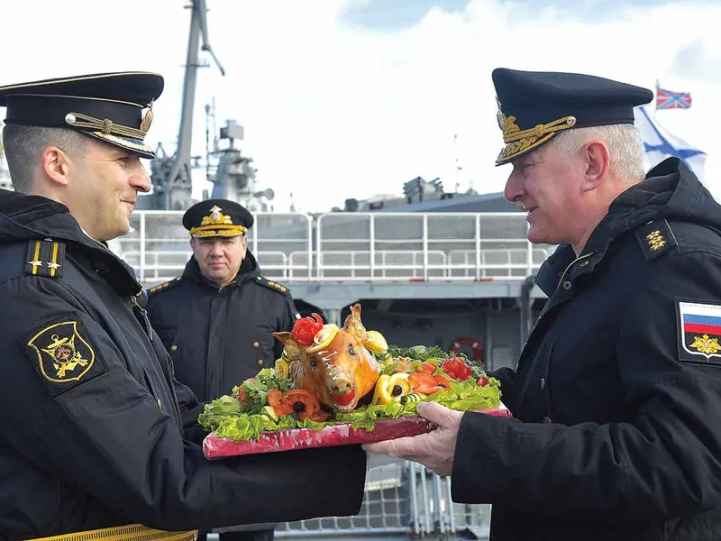 Militarii ruși oferă, tradițional, un porc prăjit în timpul unei ceremonii de întâmpinare pentru fregata Amiralului Kasatonov, la baza Flotei de Nord a Rusiei  - Foto: Getty Images