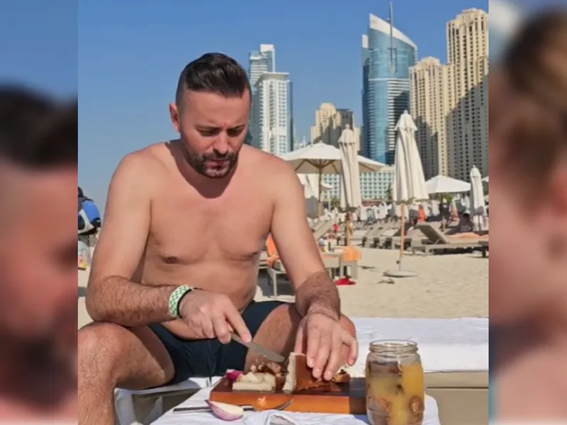 Cuplu de români, cu slănina, ceapa și pălinca pe o plajă din Dubai: În spatele nostru e Burj al-Arab - Foto: Captură Video - Florin Cilica / TikTok