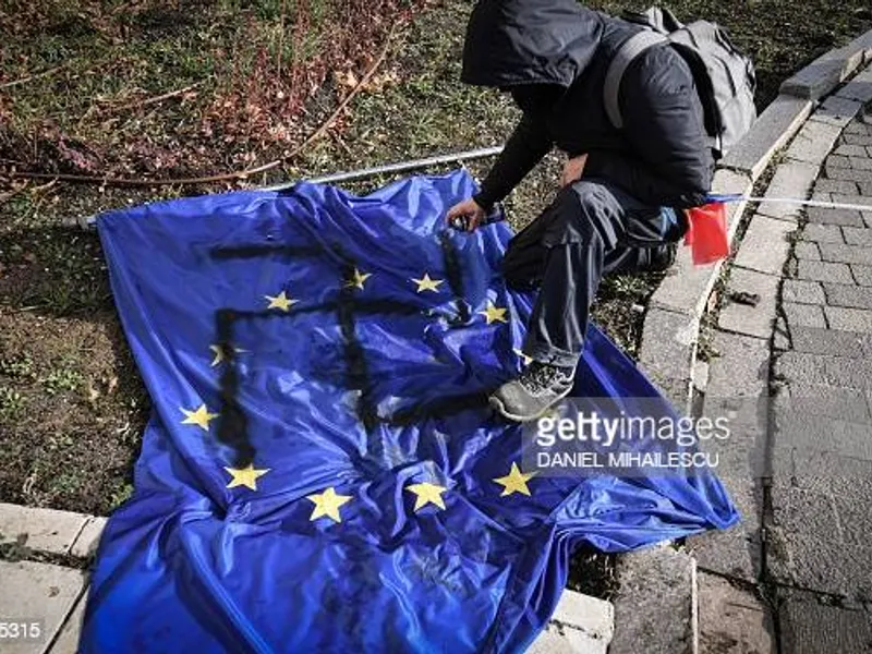 Protestatar AUR desenează svastica pe steagul UE. Sursă imagine: AFP, Daniel Mihăilescu/ Getty Images