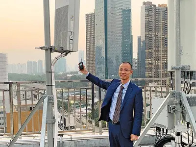 Un angajat al China Telecom compară o stație 4G, dreapta, cu versiunea 5G. Rețelele 5G pot suporta o cantitate mult mai mare de date