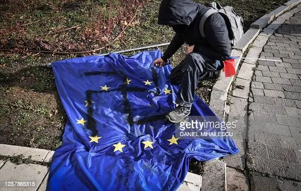 Protestatar AUR desenează svastica pe steagul UE. Sursă imagine: AFP, Daniel Mihăilescu/ Getty Images