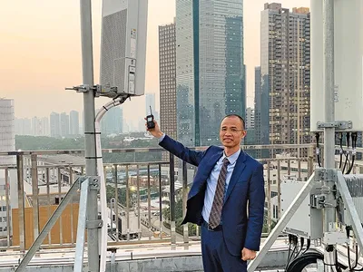 Un angajat al China Telecom compară o stație 4G, dreapta, cu versiunea 5G. Rețelele 5G pot suporta o cantitate mult mai mare de date