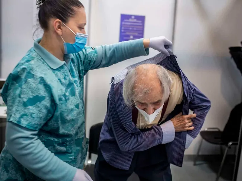 Petre Negut (91) dressing up after receiving the Pfizer-BioNTech COVID-19 vaccine at Romexpo in Bucharest, Romania Photo: Mugur VARZARIU/Getty Images/Newsweek