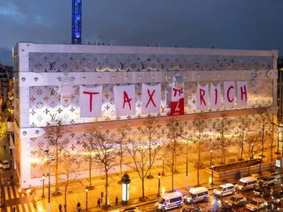 Un banner uriaş cu „Taxaţi-i pe bogaţi”, pus pe fațada viitorului hotel Vuitton din Paris - Foto: Profimedia Images